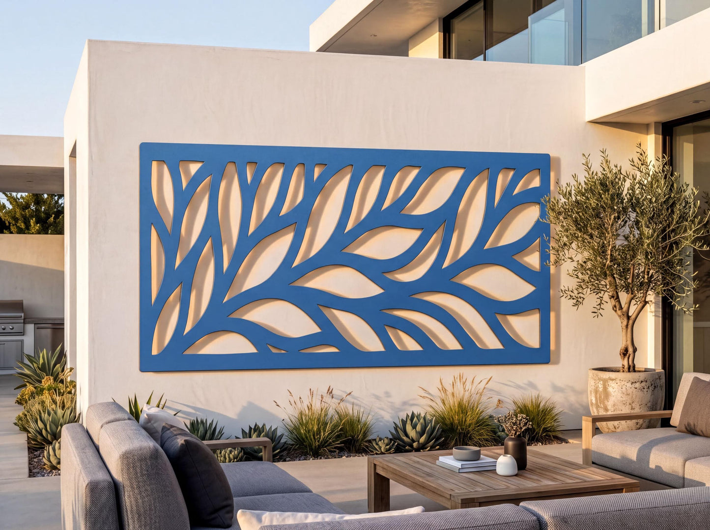 a modern outdoor living space with a large blue wall art piece depicting a leaf-like pattern. The space includes a patio with a wooden table and chairs, as well as potted plants and other decorative elements.
