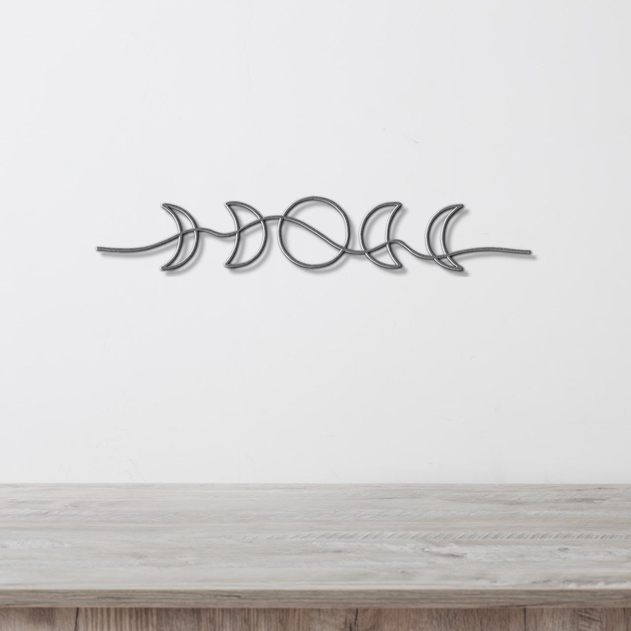 A metal wall art piece depicting the phases of the moon in a linear arrangement.