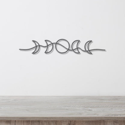 A metal wall art piece depicting the phases of the moon in a linear arrangement.