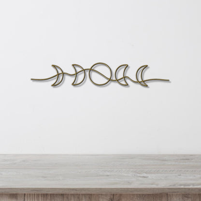 A decorative metal wall hanging depicting the phases of the moon in a linear arrangement.