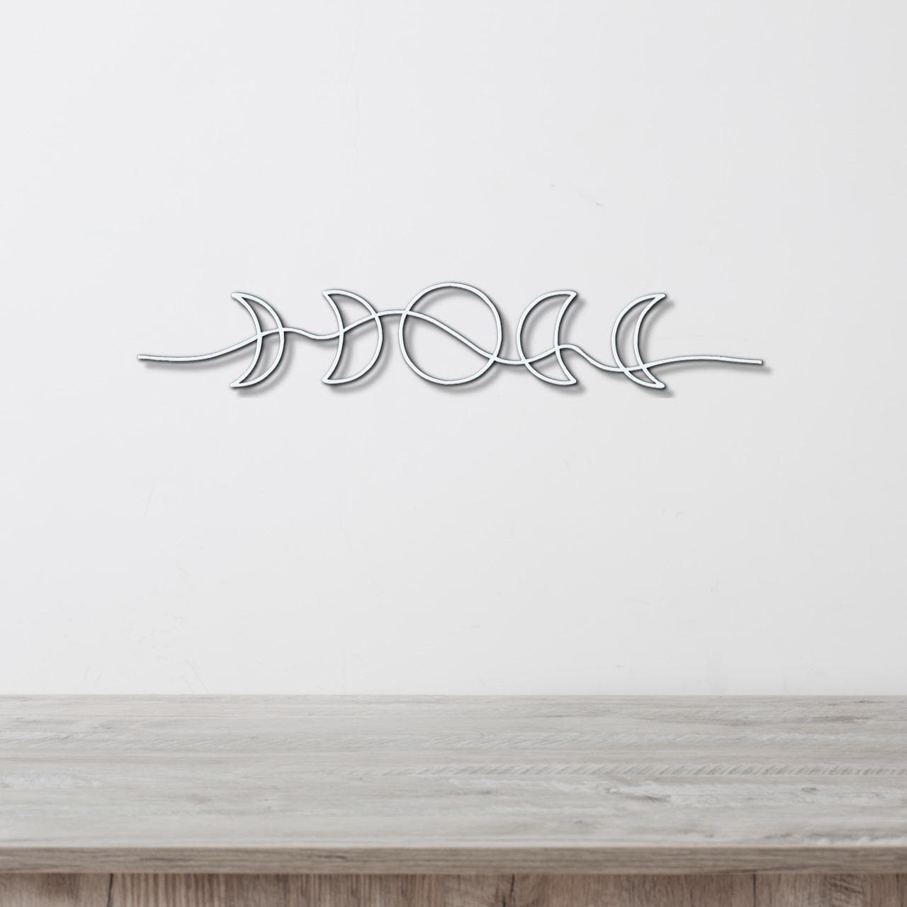 A metal wall art piece depicting the phases of the moon in a minimalist design.