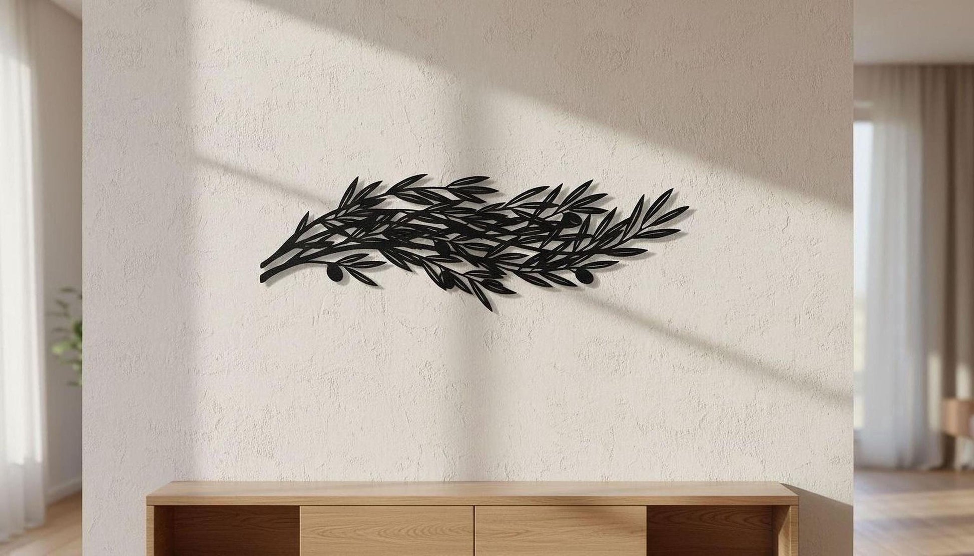 a black metal sculpture of a branch with leaves, mounted on a white wall in a room with a wooden cabinet below it.