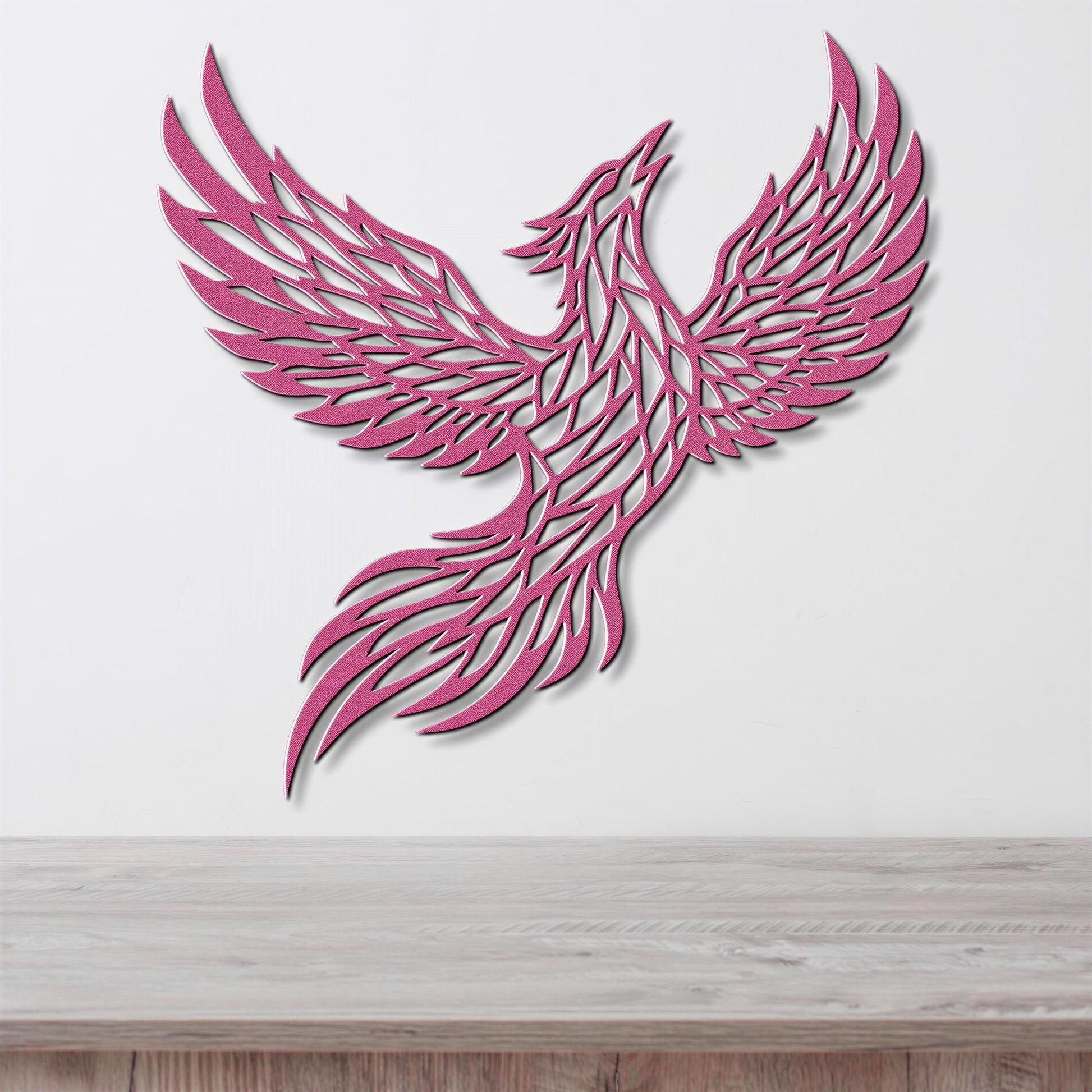 A pink, stylized bird-like figure with outstretched wings is displayed on a white wall above a wooden surface.