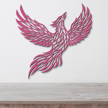 A pink, stylized bird-like figure with outstretched wings is displayed on a white wall above a wooden surface.