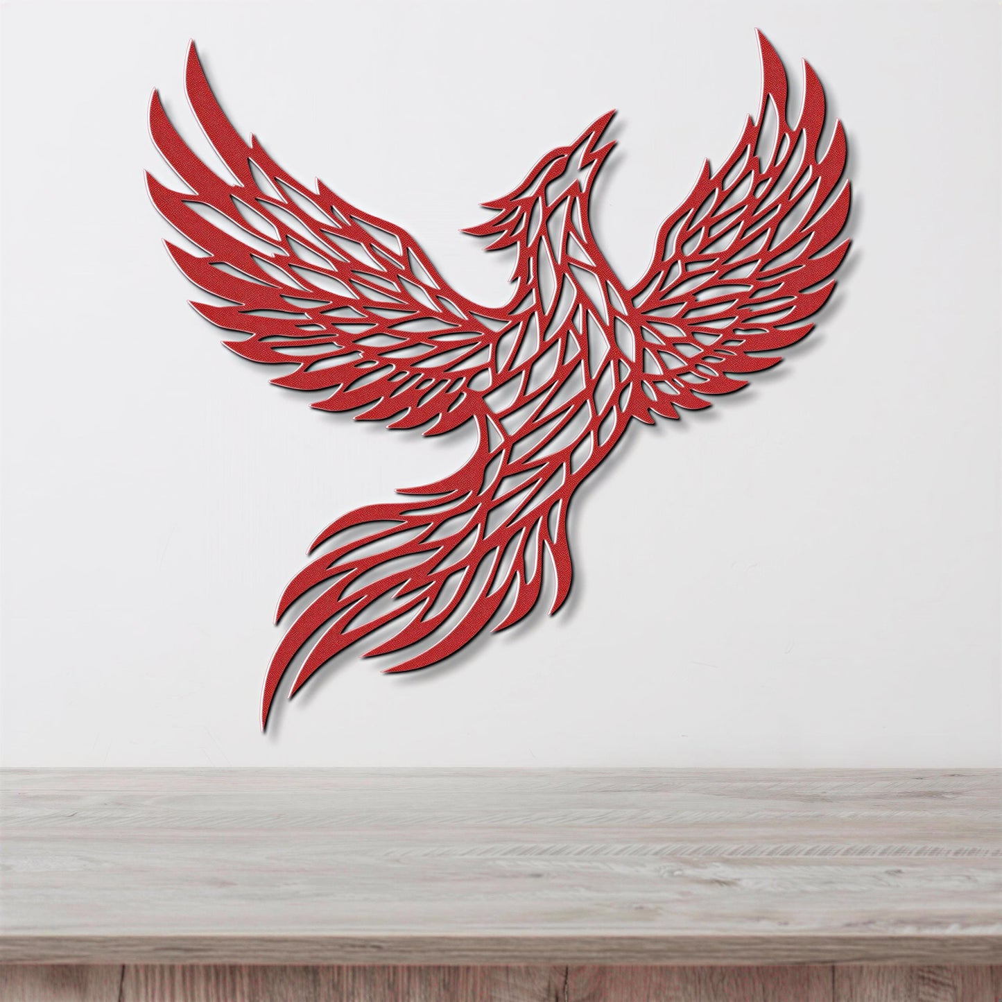 A red, stylized bird-like figure with outstretched wings is displayed on a white wall above a wooden surface.