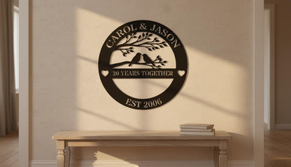 a wall-mounted sign that reads "CAROL & JASON 20 YEARS TOGETHER EST 2006" with a tree and two birds on a branch. Below the sign, there is a wooden bench with a stack of books on it.