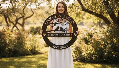 A woman in a white dress stands in a garden, holding a large sign that says "CAROL & JASON 20 YEARS TOGETHER EST 2006".