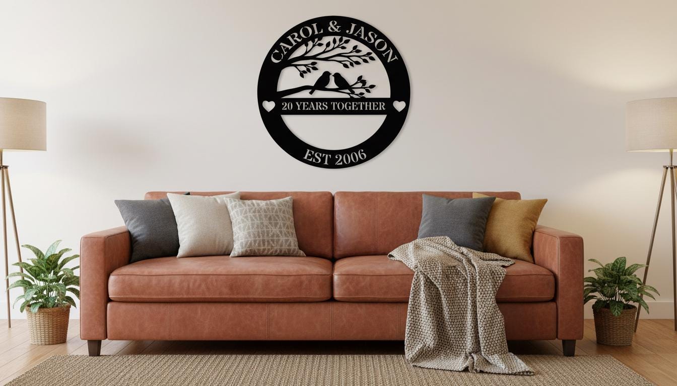 a living room with a brown leather couch adorned with throw pillows and a blanket. Above the couch, there is a black circular metal sign with the text "CAROL & JASON" and "20 YEARS TOGETHER" written on it. The sign is mounted on a white wall, and there are two floor lamps on either side of the couch.