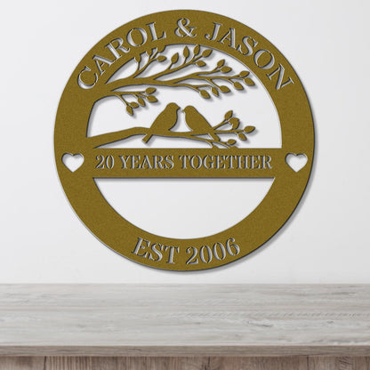 A gold-colored metal sign with the text "CAROL & JASON" and "20 YEARS TOGETHER EST 2006" on it, along with a tree silhouette and two birds.