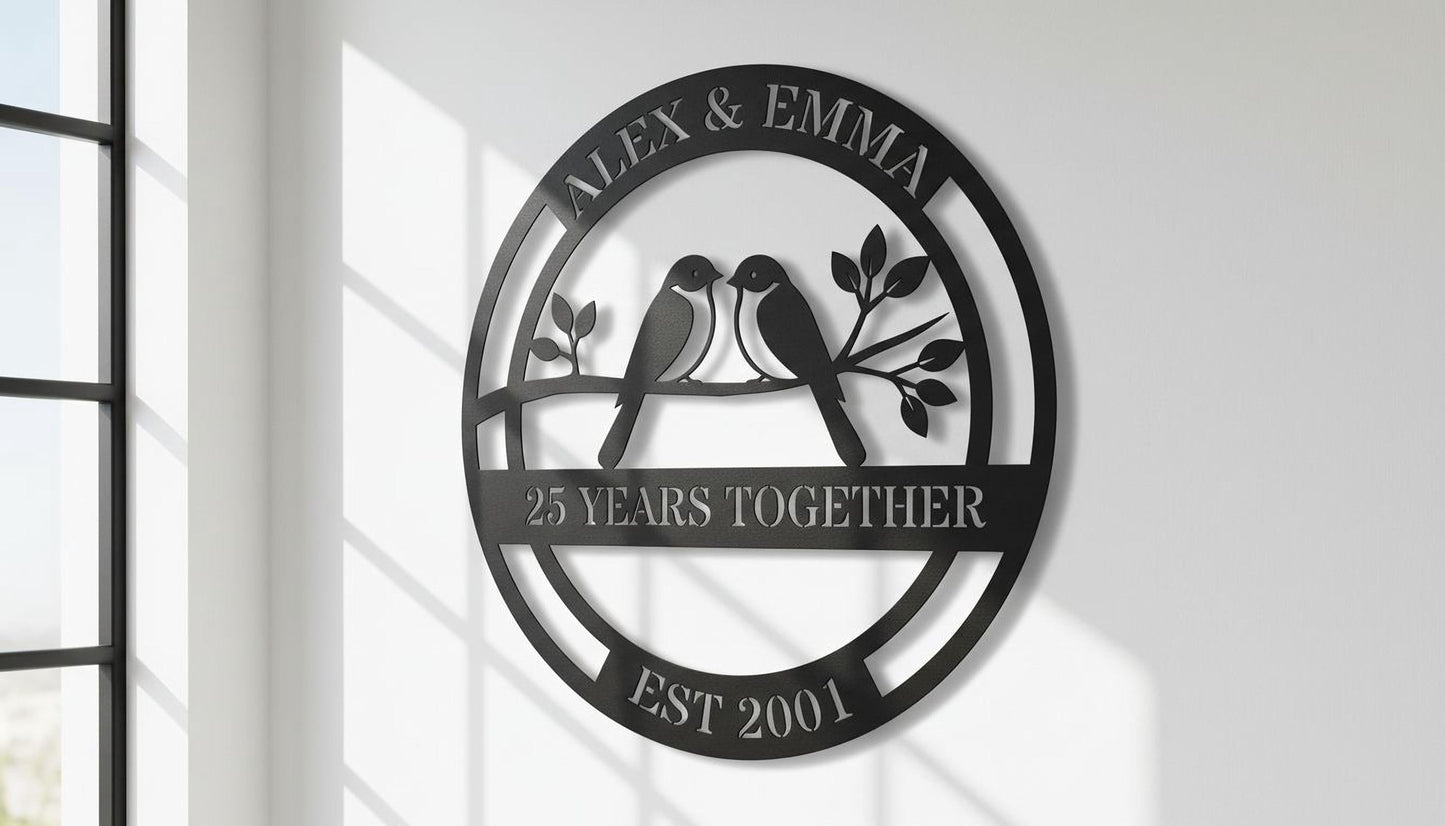 A black metal sign with the text "Alex & Emma" and "25 YEARS TOGETHER EST 2001" on it, along with a graphic of two birds sitting on a branch.
