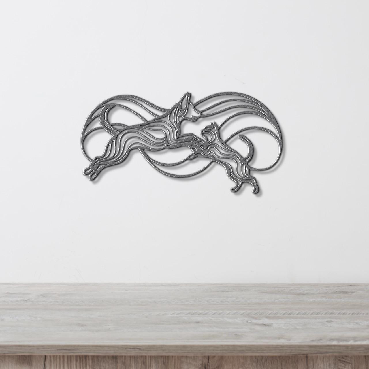 A decorative metal wall art piece depicting two stylized dogs in mid-leap, with flowing lines and curves creating a dynamic and abstract design.