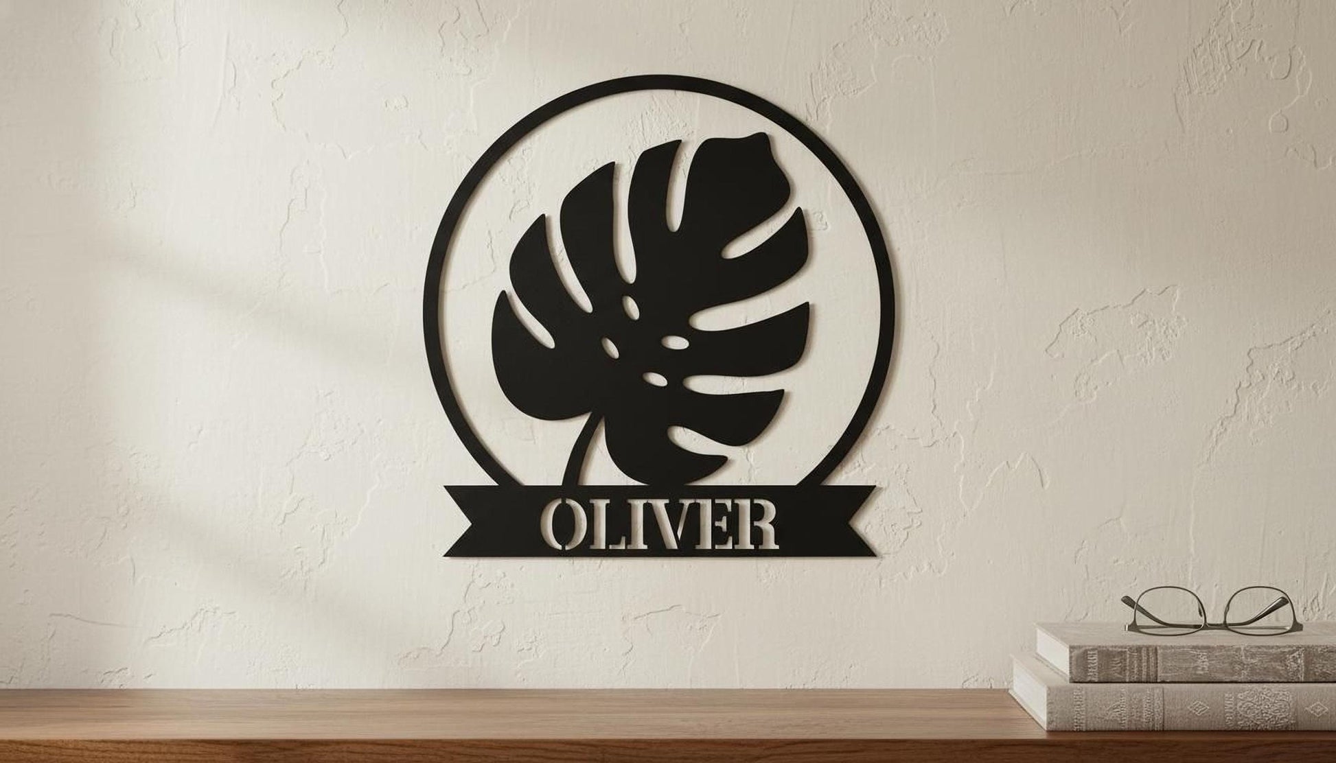 a wall decoration with a large leaf-shaped design and the name "OLIVER" below it, mounted on a wall.