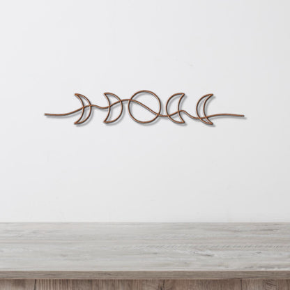 A decorative metal wall hanging depicting the phases of the moon in a linear arrangement.