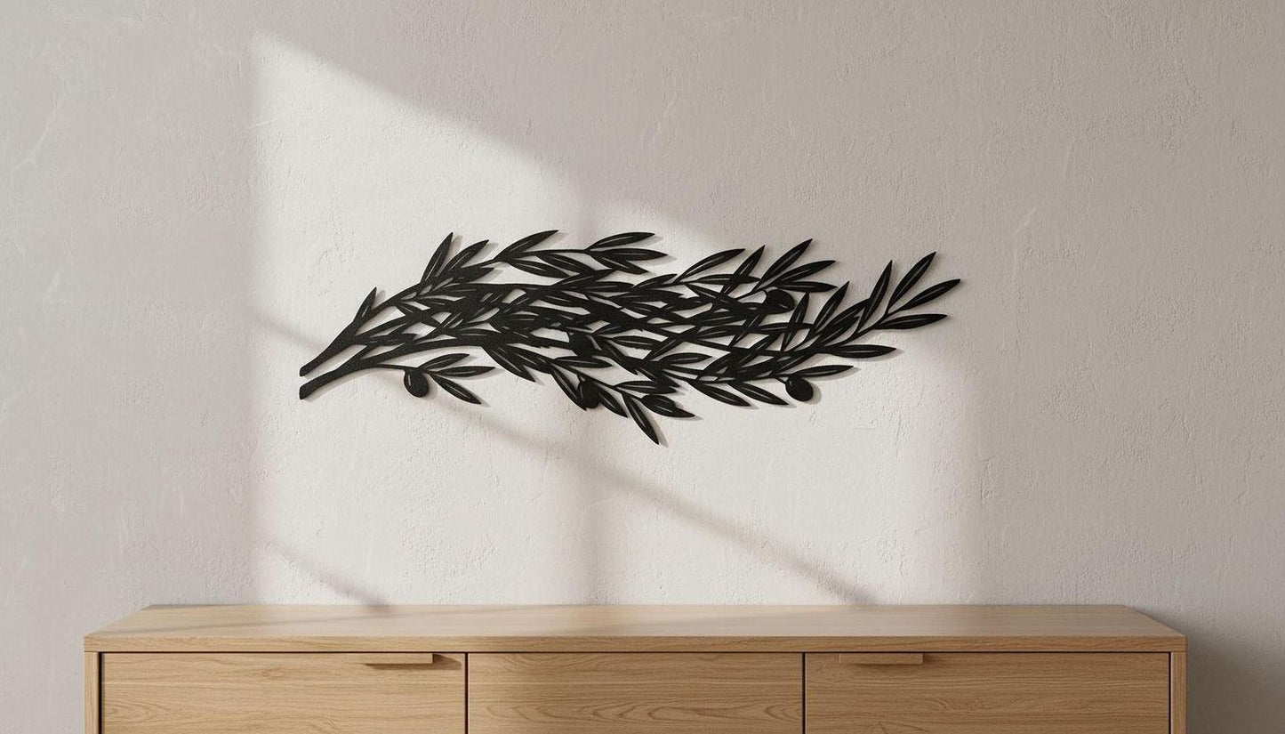 A black metal leaf sculpture is mounted on a white wall above a wooden cabinet or dresser.