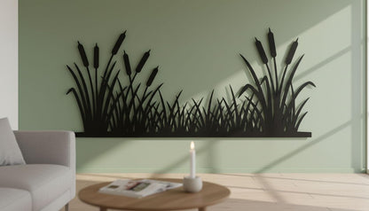 a living room with a green wall that has a large black silhouette of reeds or grasses. In front of the wall, there is a wooden coffee table with a lit candle on it. A couch is placed against the wall, and a magazine is visible on the coffee table.