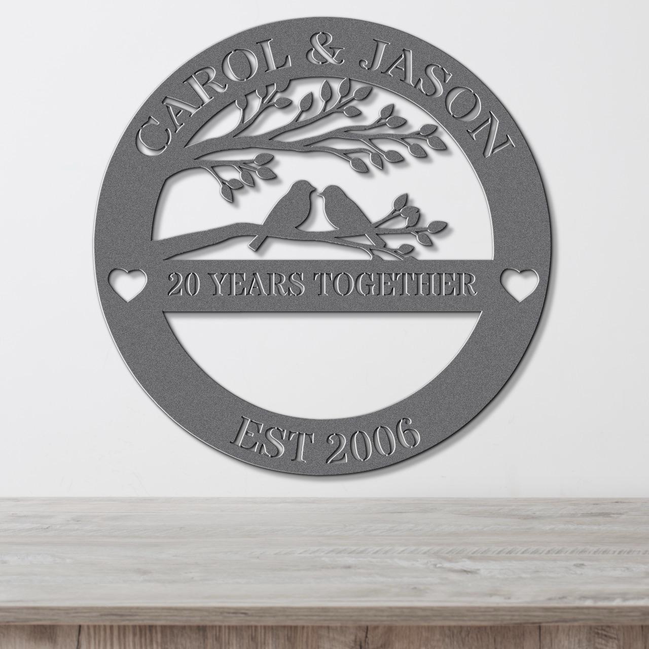 A metal sign with the text "CAROL & JASON" and "20 YEARS TOGETHER" along with a tree and birds, indicating a 20-year commitment between the couple.