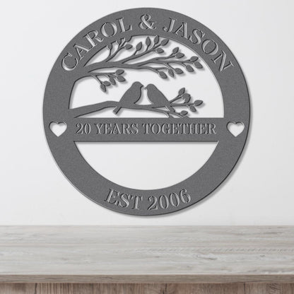 A metal sign with the text "CAROL & JASON" and "20 YEARS TOGETHER" along with a tree and birds, indicating a 20-year commitment between the couple.