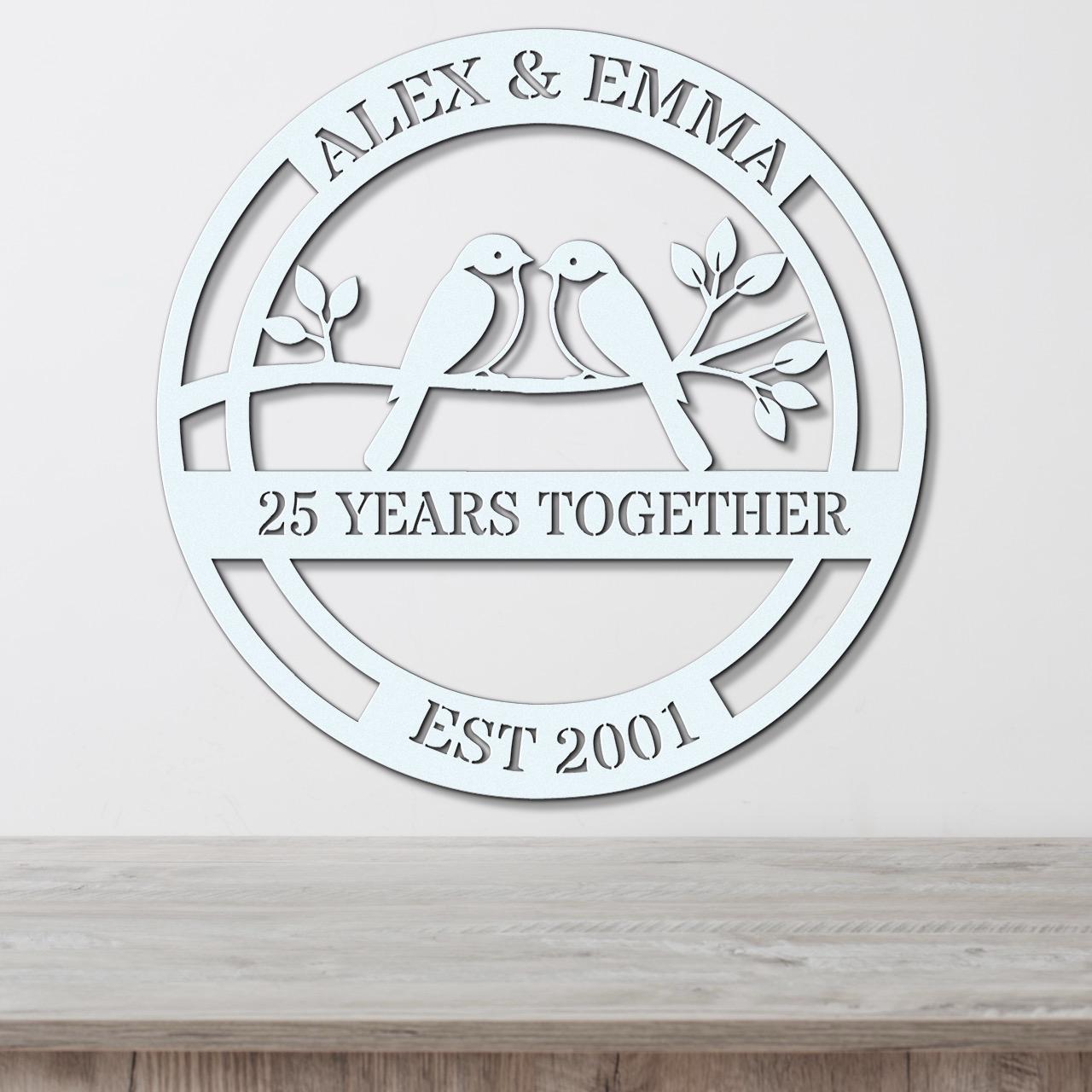 A white circular wall hanging with the text "ALEX & EMMA 25 YEARS TOGETHER EST 2001" and a graphic of two birds sitting on a branch.