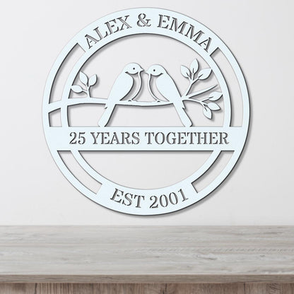 A white circular wall hanging with the text "ALEX & EMMA 25 YEARS TOGETHER EST 2001" and a graphic of two birds sitting on a branch.