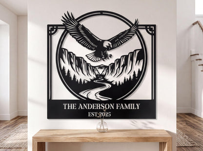 a large black and white metal wall art depicting an eagle in flight above a mountain landscape, with a river below. The text "THE ANDERSON FAMILY EST.2025" is displayed below the artwork.