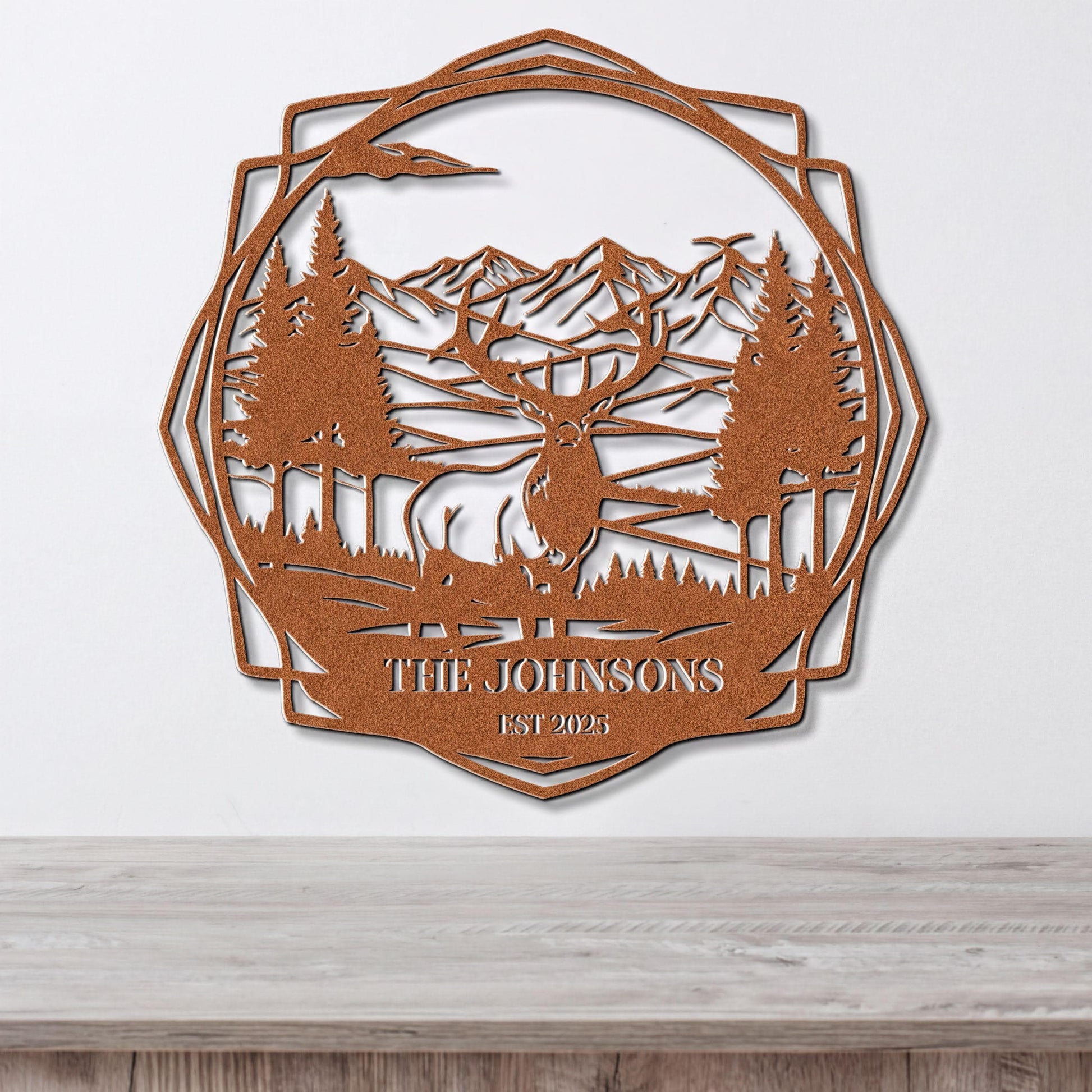 a decorative metal wall hanging depicting a deer in a forest setting with mountains in the background.