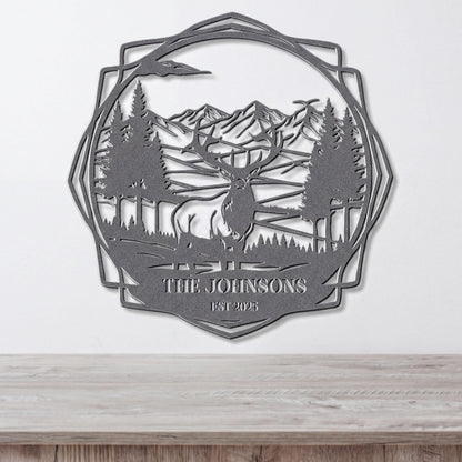A metal wall art piece depicting a deer in a forest setting with mountains in the background.