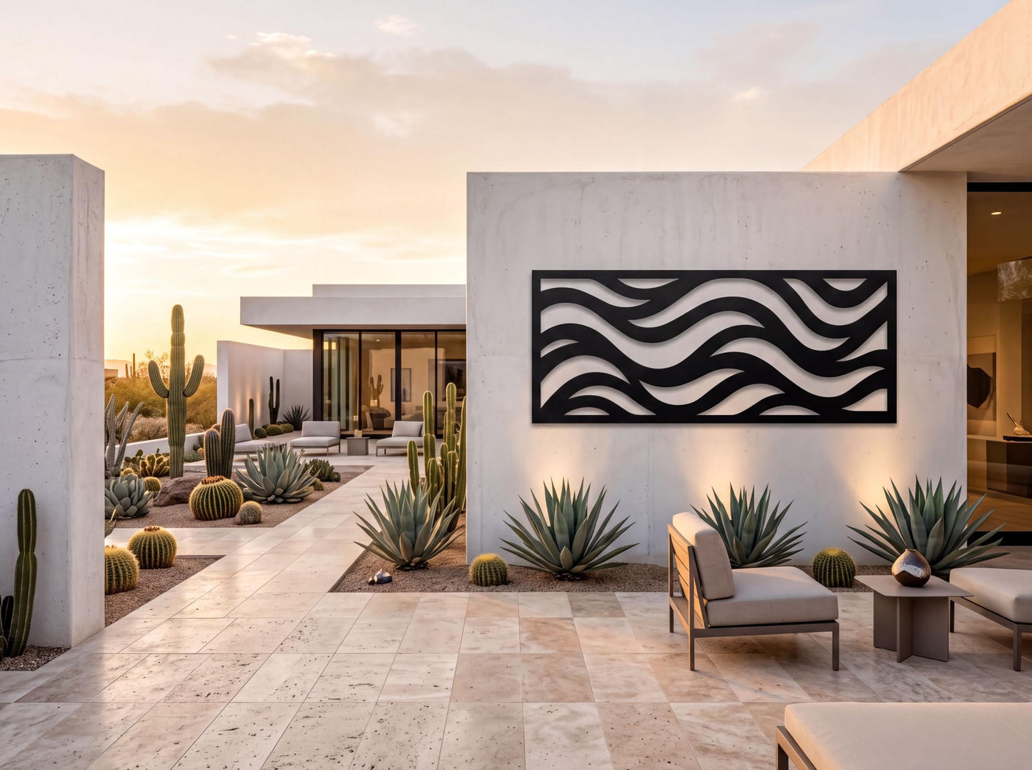 a modern, minimalist outdoor living space with a large, abstract wave-like design on the wall. The space is surrounded by various cacti and succulents, creating a desert-inspired ambiance. The patio area is furnished with comfortable seating, including a sofa and chairs, providing a relaxing environment for outdoor living. The overall design and layout of the space suggest a contemporary and luxurious residential setting.