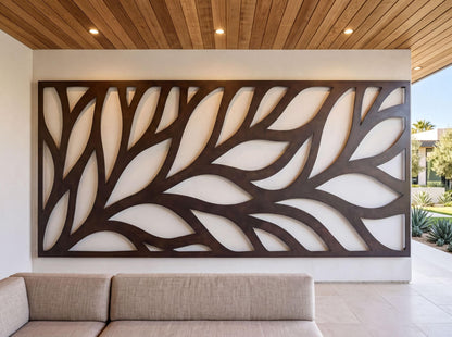 a modern living room with a large, abstract wall art piece composed of curved lines and shapes in a dark color. In the foreground, there is a beige sofa, and the room has a wooden ceiling with recessed lighting.