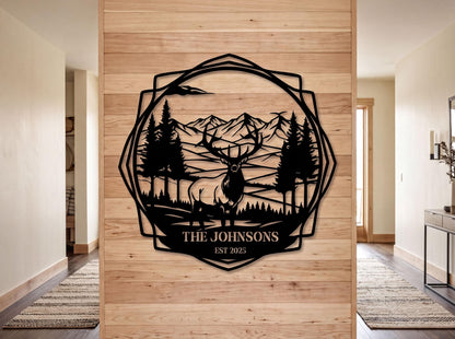 a wooden wall with a decorative metal design depicting a deer in a forest setting, surrounded by mountains. The text "THE JOHNSONS EST. 2005" is displayed below the deer, indicating the name and year of the family.