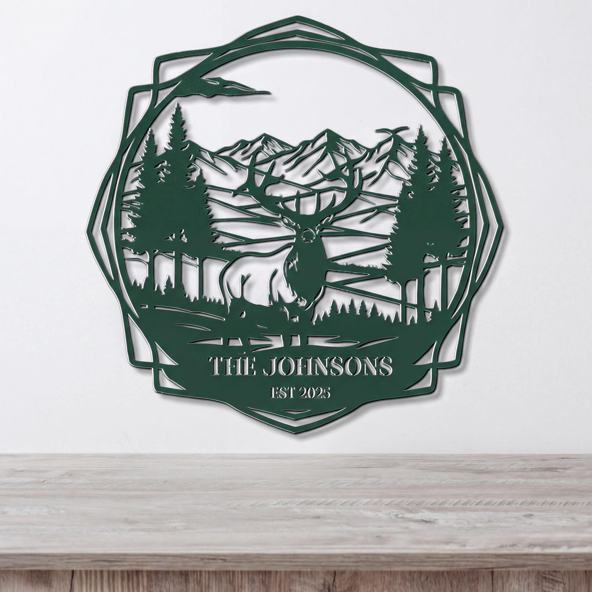 A metal wall art piece depicting a deer in a forest setting with mountains in the background.