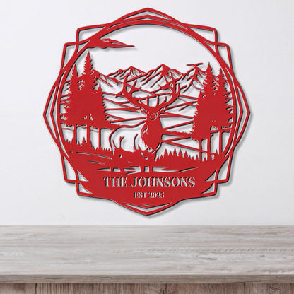 A red metal wall hanging depicting a deer in a forest setting with mountains in the background.