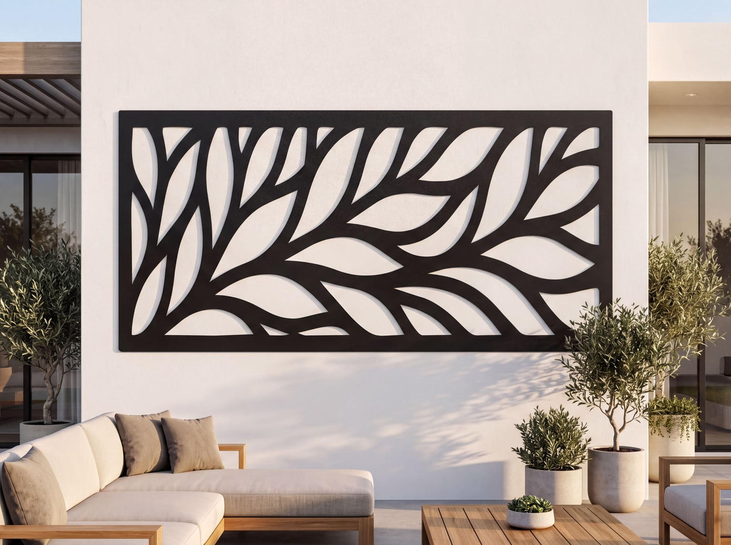 a modern outdoor living space with a large black and white leaf-like design on the wall behind a seating area. The seating area includes a couch and a coffee table, and there are potted plants and a wooden table nearby.