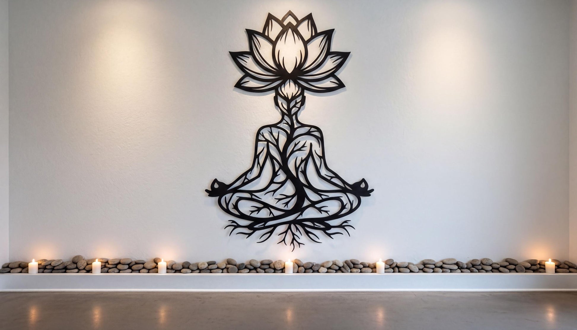 a wall with a large black and white design of a seated Buddha figure surrounded by a lotus flower and roots, with candles in front of it.