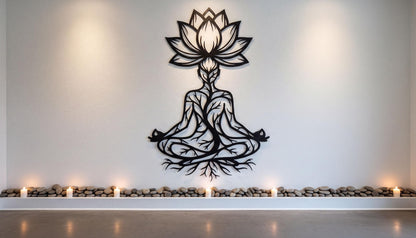 a wall with a large black and white design of a seated Buddha figure surrounded by a lotus flower and roots, with candles in front of it.