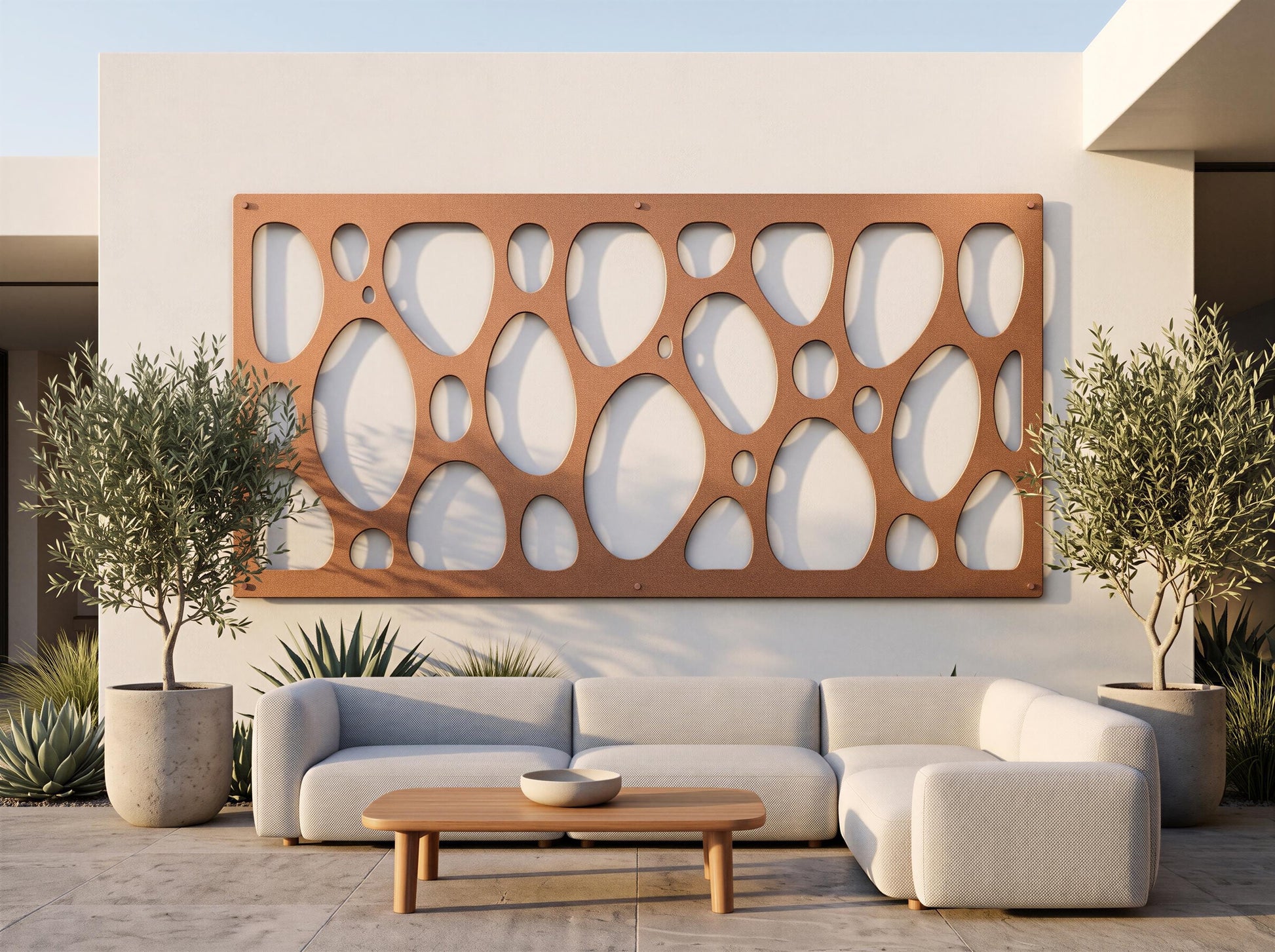 a modern outdoor living space with a white sofa, a wooden coffee table, and two potted plants. The sofa is positioned in front of a wall with a unique circular pattern, creating a visually appealing focal point.