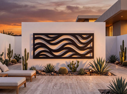 a modern outdoor living space with a white wall featuring a large black wave-like design. The space is surrounded by various desert plants, including cacti and succulents, creating a serene and natural atmosphere. The scene is illuminated by warm lighting, enhancing the overall ambiance of the space.