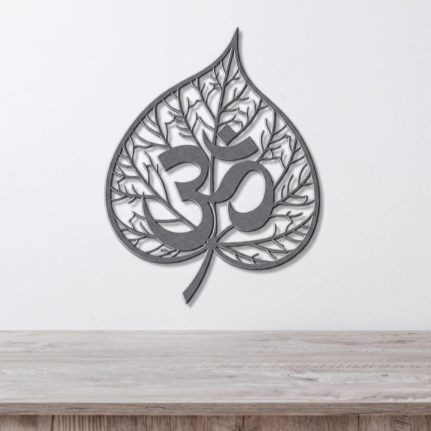 A metal leaf-shaped wall art piece with the Om symbol in the center.