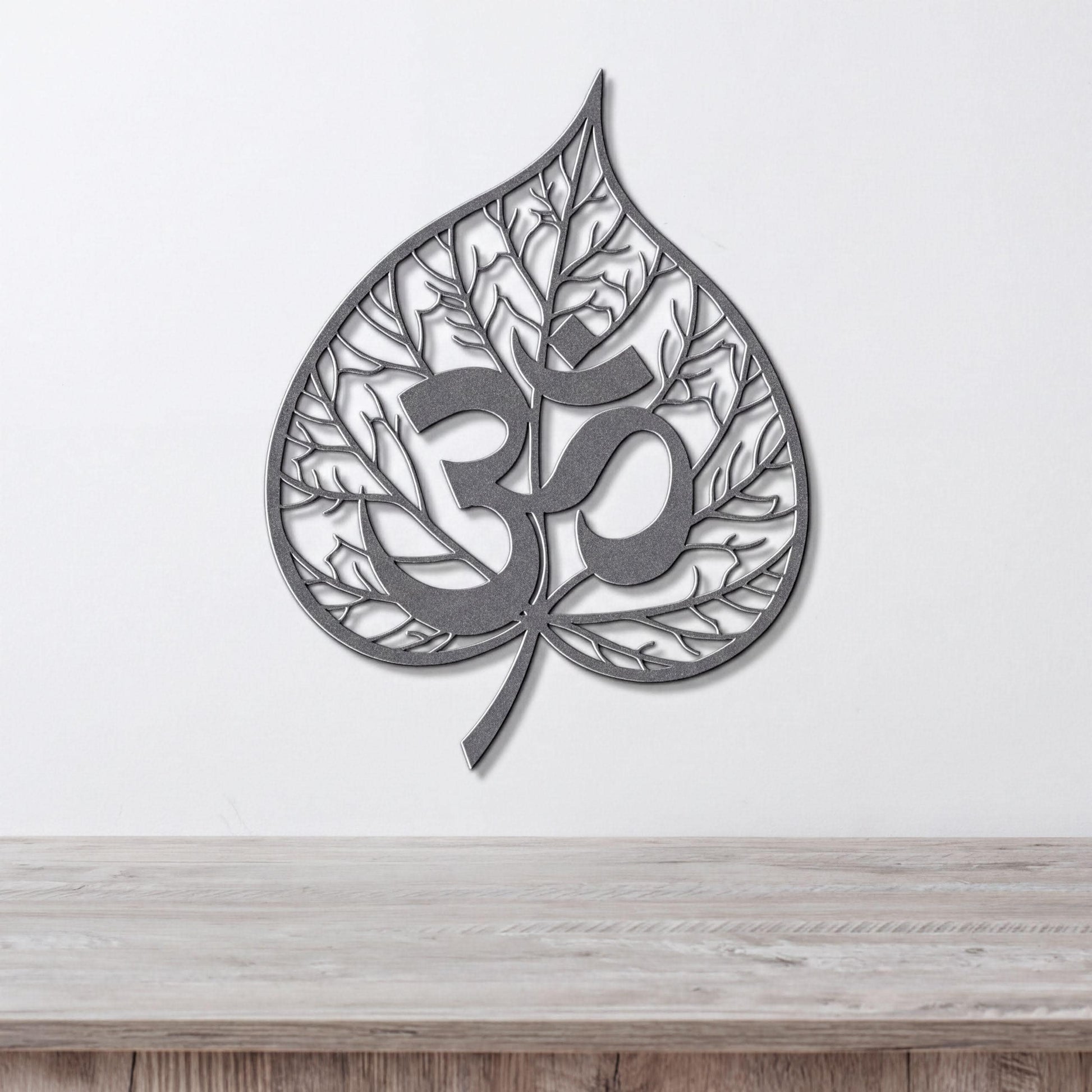 A metal leaf-shaped wall art piece with the Om symbol in the center.