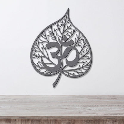A metal leaf-shaped wall art piece with the Om symbol in the center.